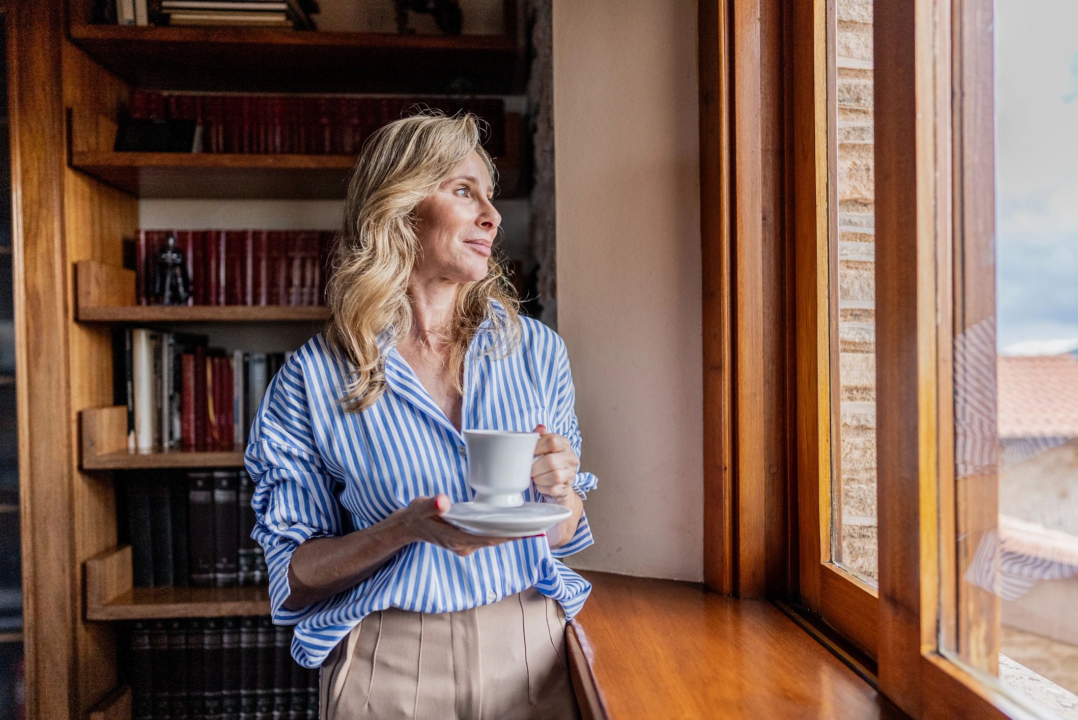Mature woman looking out a window at home