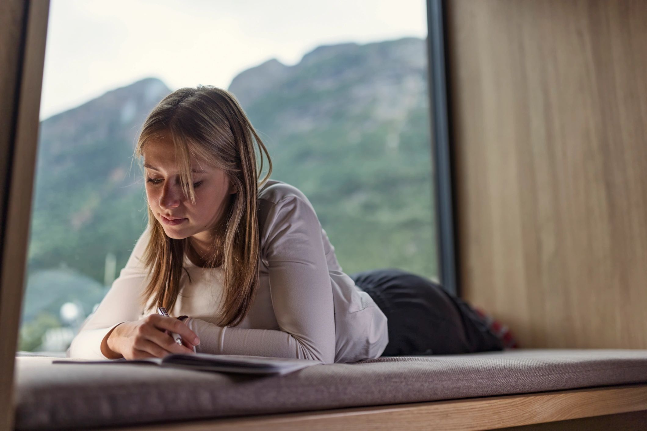 Woman writing by a large window