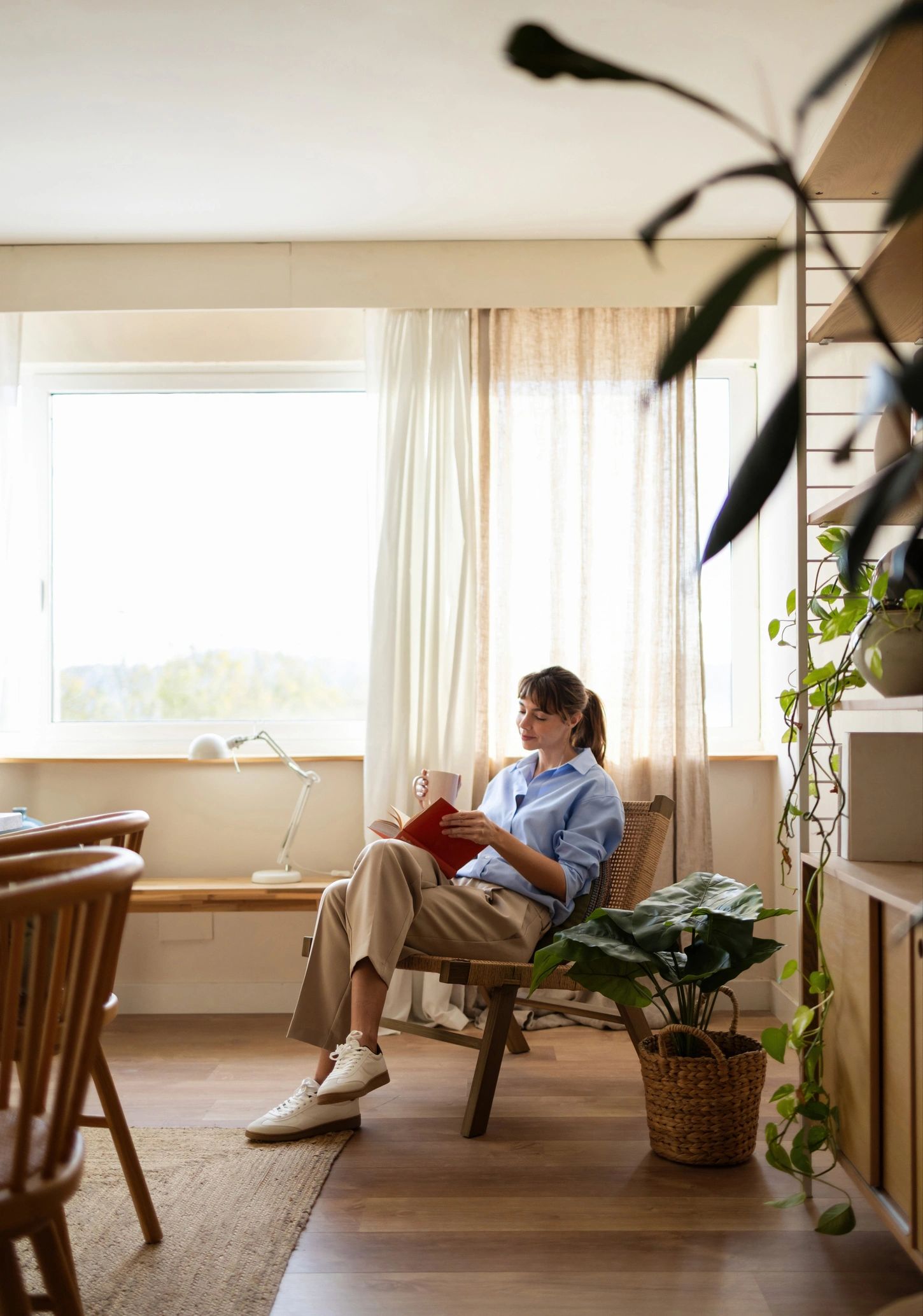 Woman reading by a window in a calm, bright room